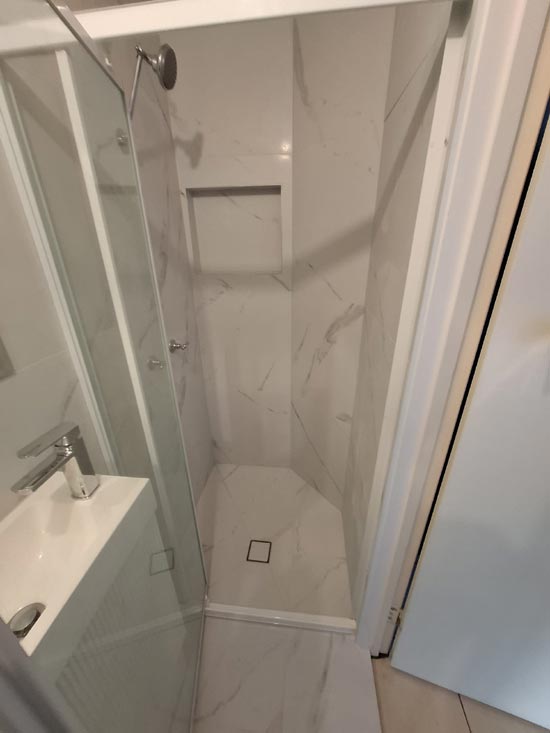 Completed bathroom with a marble-tiled shower niche