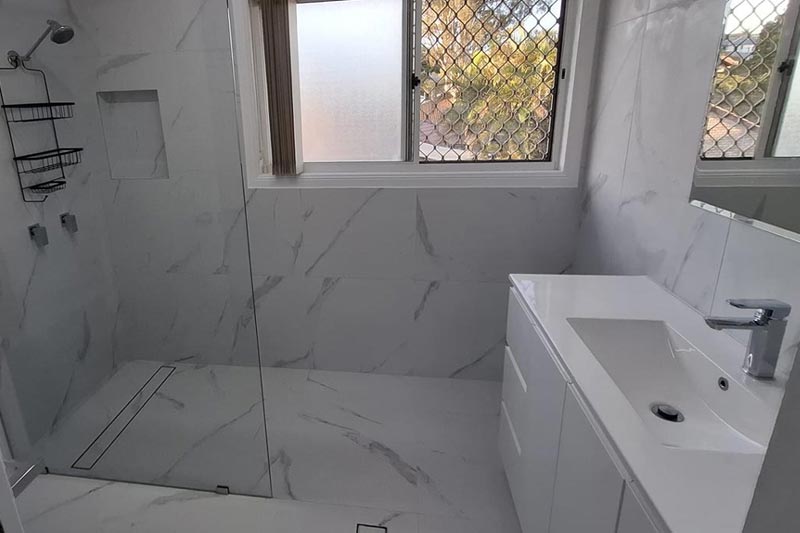 Completed bathroom in white marble with a linear shower drain